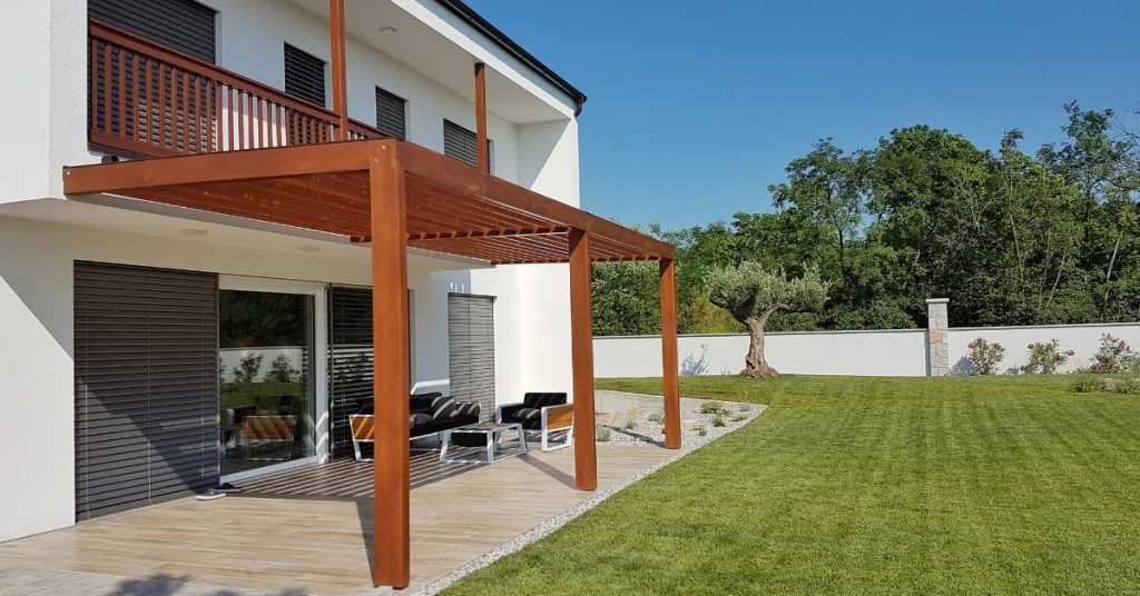 House with a wooden pergola and balcony in the backyard.